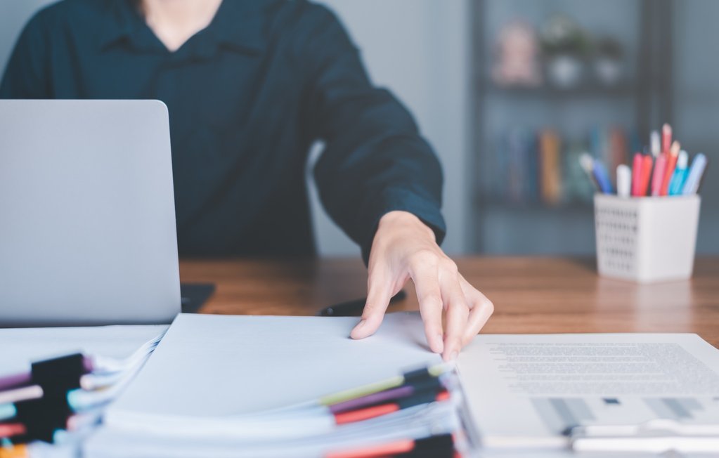 Close-up of a person organizing paperwork at a desk.