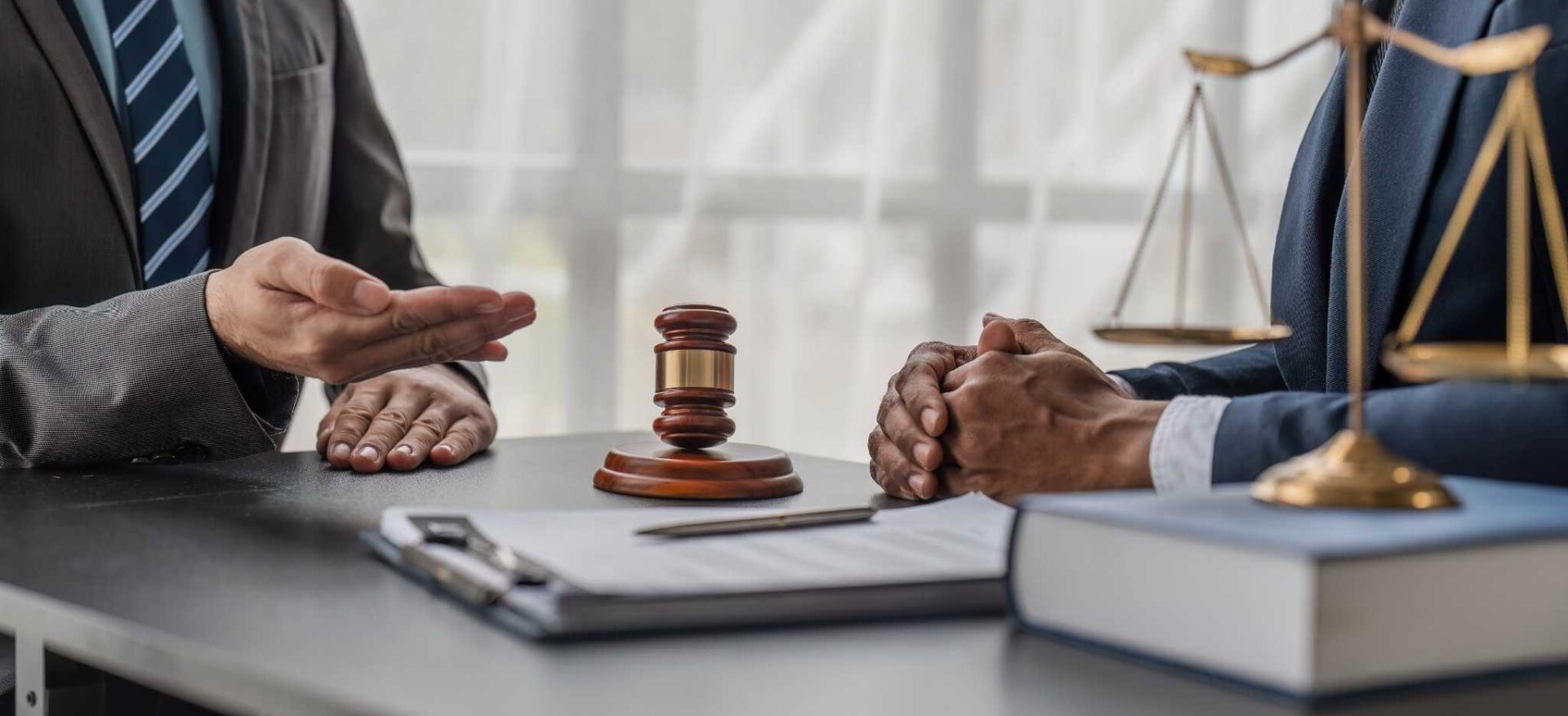 Legal professionals discussing a case with a gavel and scales of justice on the table.
