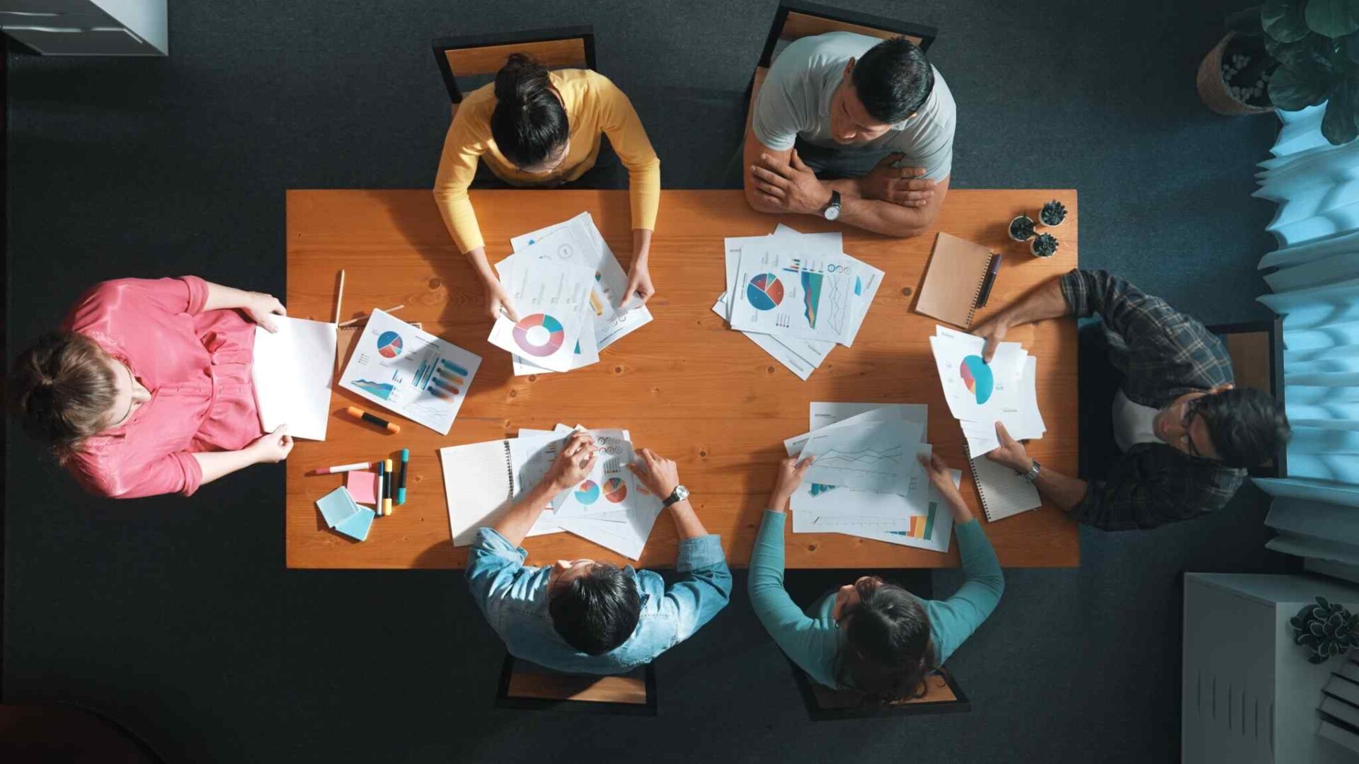 Top view of a team analyzing charts and graphs at a meeting table.