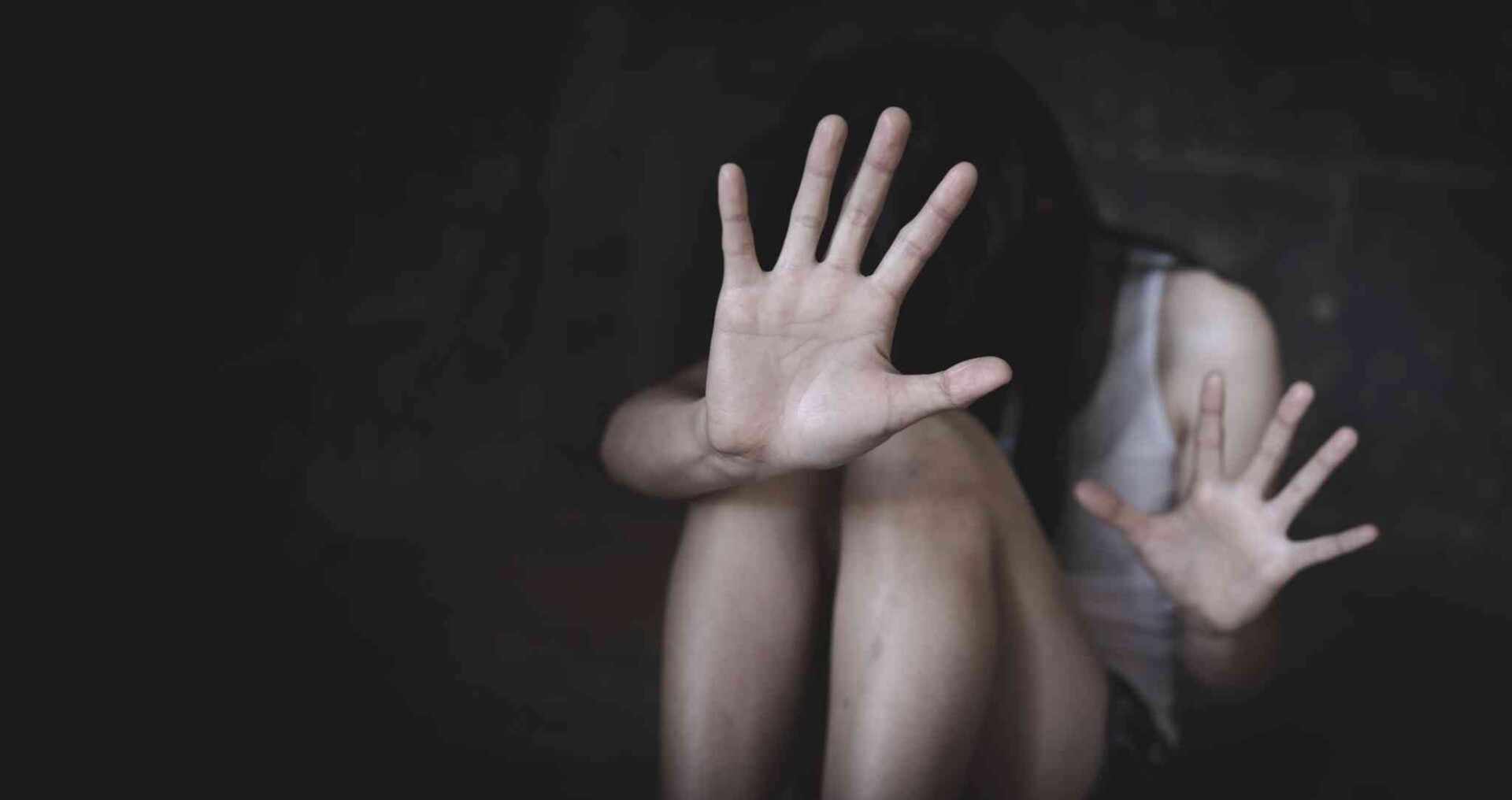 Victim shielding themselves, highlighting domestic violence.