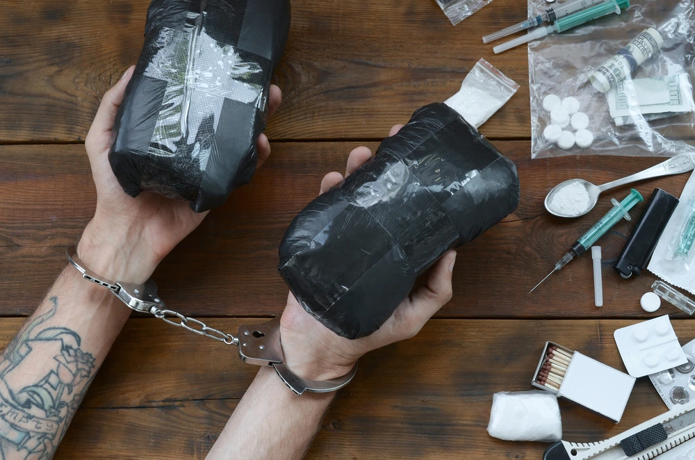 Drug dealer arrested with narcotics on table.