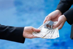 Hand holding banknotes of the Japanese yen and house model.