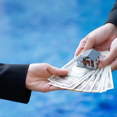 shutterstock_1028546500 Hand holding banknotes of the Japanese yen and house model.
