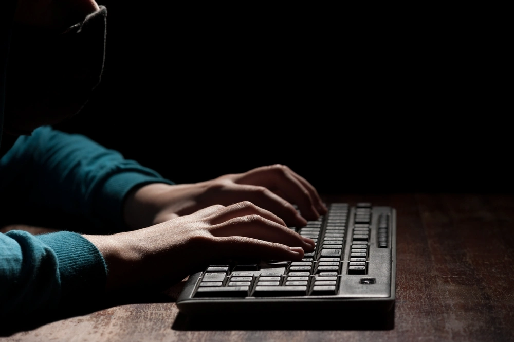 Unknown person hands using a keyboard sends message with intimidating and threatening.
